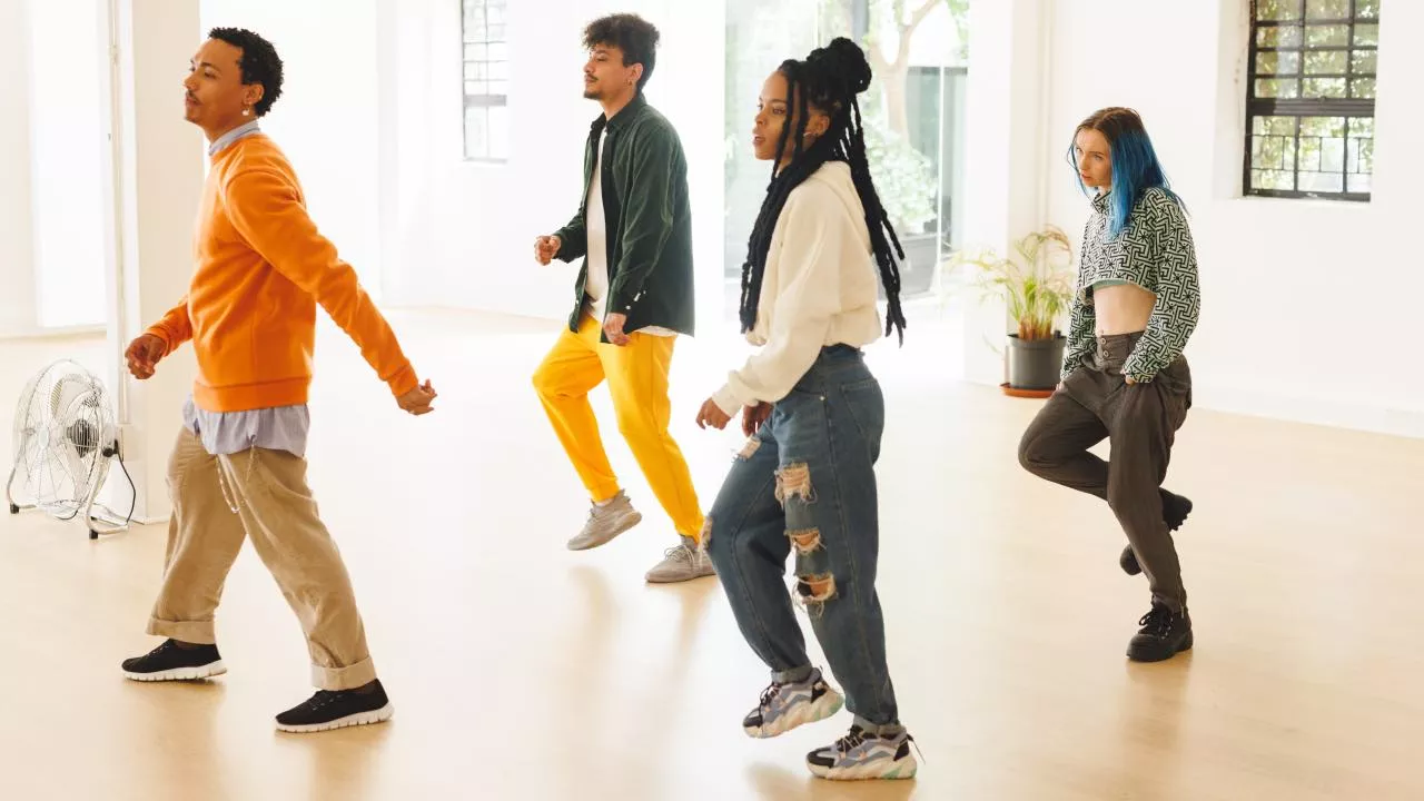 Dos chicas y dos chicos aprendiendo a bailar en clase, concentrados en los movimientos.