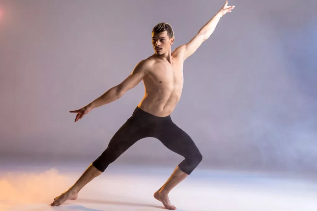 Chico ejecutando un movimiento de danza contemporánea con el método Horton, demostrando fuerza y control.