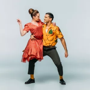 Pareja de bailarines de teatro musical ejecutando una coreografía expresiva en el escenario.