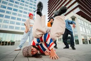 Historia de la danza urbana: chico haciendo un giro en el suelo mientras dos chicas bailan y animan.