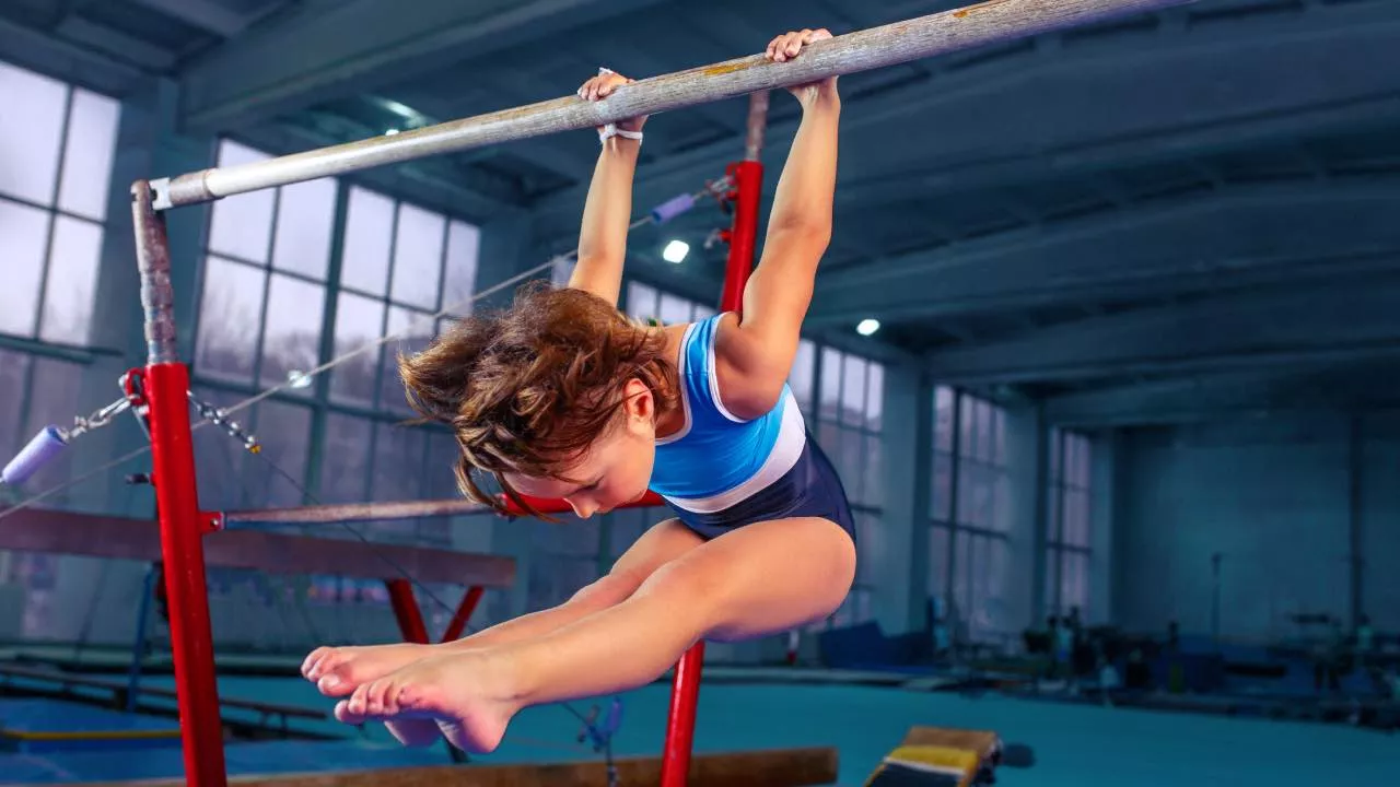 Historia y origen de la gimnasia: niña practicando un ejercicio en la barra.