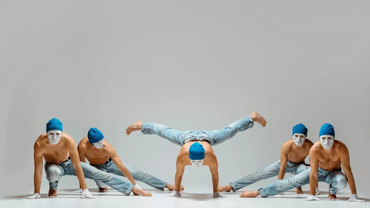 Cinco chicos bailando danza contemporánea estilo Graham, ejecutando movimientos acrobáticos y complejos.