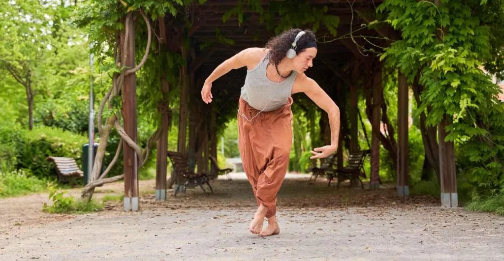 Chica en posición de danza contemporánea con cascos, practicando Mindfulness y danza.