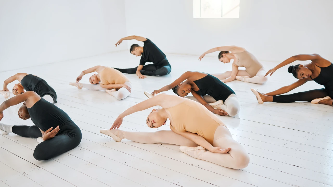 Grupo de chicos y chicas haciendo estiramientos antes de la clase de danza.